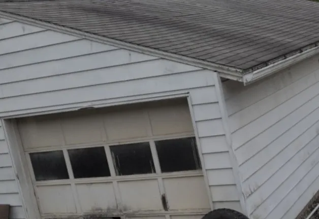 Detached white garage with a worn, discolored shingle roof